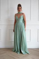 Woman wearing a sage green pleated maxi gown with a strapless sweetheart neckline, ruched bodice, flowing floor-length skirt, and matching neck scarf, perfect for prom, black-tie events, bridesmaid parties, and formal occasions.