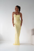 Woman wearing a yellow strapless dress against a white background