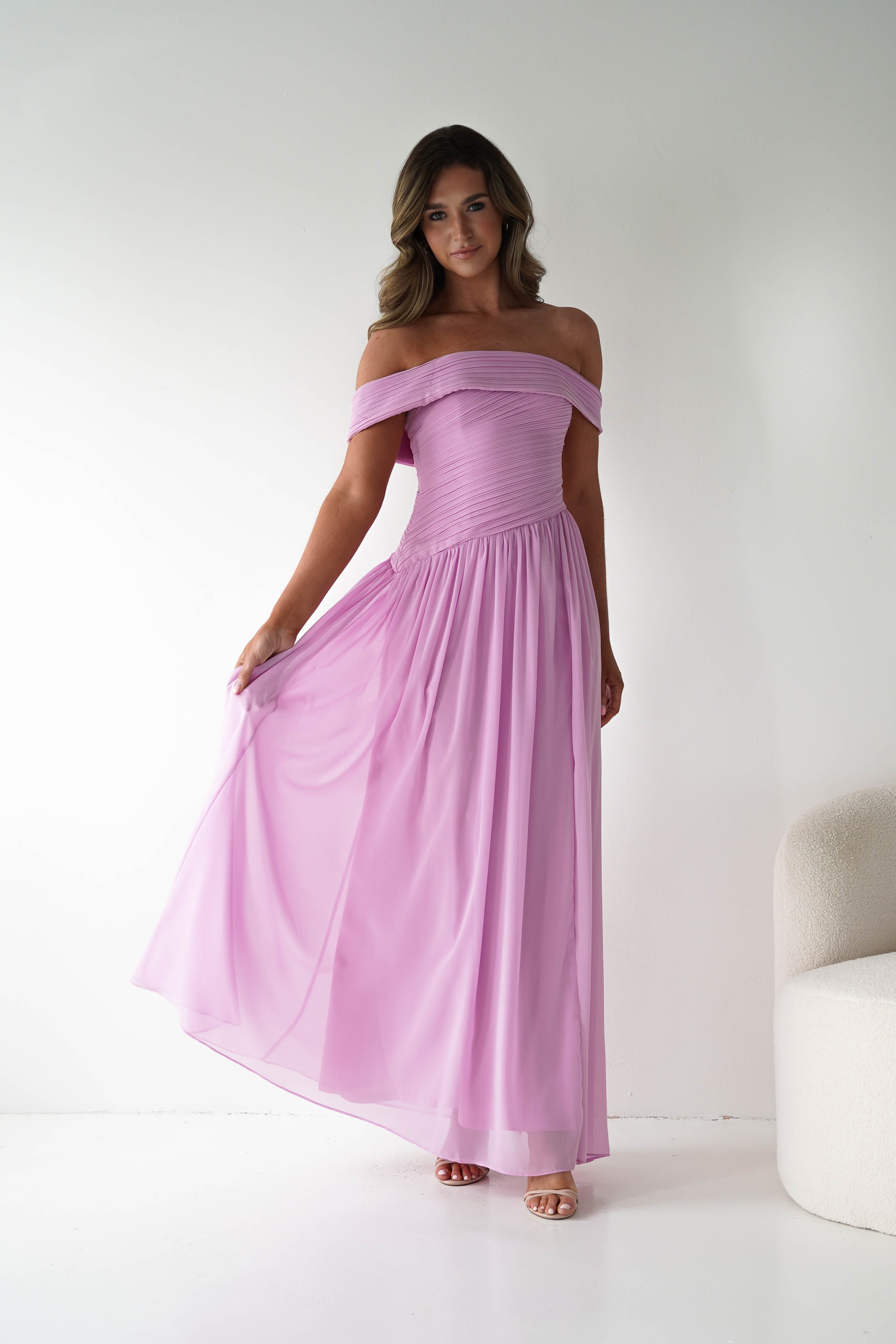Woman wearing a pink off-shoulder dress against a white background