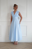 Woman wearing a baby blue midi dress with a sleeveless V-neckline, twist waist detailing, and a flowing A-line skirt, perfect for weddings, garden parties, baby showers, and special occasions.